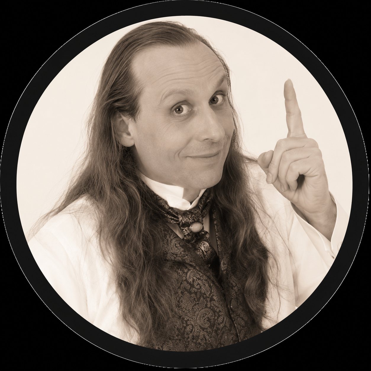 Portrait circulaire d'un homme aux longs cheveux foncés qui lève l'index, vêtu d'une veste sombre et d'une chemise claire.